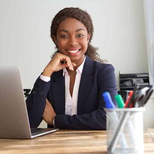 young-black-businesswoman-sitting-at-office-desk-SQZDS5W.jpg